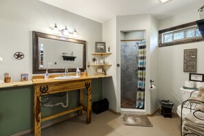 Ein Badezimmer mit einem Holzkosmetikschrank, einem großen Spiegel, einer Dusche mit gestreifter Duschvorhang und einem Schild mit Badezimmerregeln.