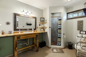 Ein Badezimmer mit einem Holzkosmetikschrank, einem großen Spiegel, einer Dusche mit gestreifter Duschvorhang und einem Schild mit Badezimmerregeln.