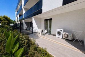 Ein modernes Gebäude mit Balkon, Außenmöbeln und Waschmaschine.
