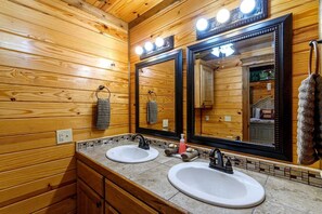 Ein Badezimmer mit Holzwänden, zwei Waschbecken, einem großen Spiegel und einem Handtuchhalter.