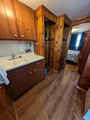 A compact kitchen with wooden cabinets, a sink, and a window. - Oceanfront Sanctuary with Elevated Coastal Comfort in North Truro, Massachusetts (North Truro)
