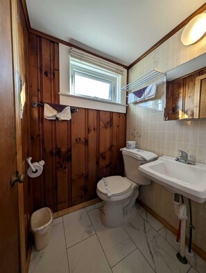A bathroom with a toilet, sink, and window. - Oceanfront Sanctuary with Elevated Coastal Comfort in North Truro, Massachusetts (North Truro)