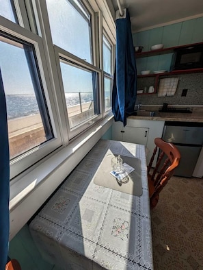 A kitchen with a window, a table with a lace tablecloth, and a chair. - Beachside Retreat with Fresh Ocean Air in North Truro, Massachusetts (North Truro)