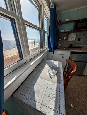 Eine Küche mit Fenster, einem Tisch mit weißer Spitze und einem Stuhl.