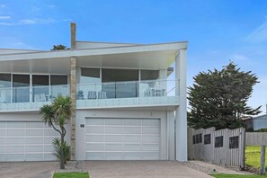 Ein modernes, zweistöckiges Haus mit Garage, Balkon und umzäuntem Garten.