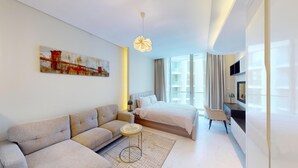 Moderni hotellihuone, jossa on sohva, sänky, taideteoksia ja televisio.