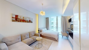 A modern hotel room with a sofa, bed, artwork, and a television. - Elegant Studio in Bahrain Bay in Waterbay (Manama)