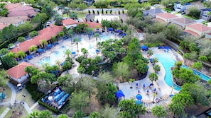 Eine Vogelperspektive zeigt ein Resort mit mehreren Schwimmbecken, Liegebereichen und verschiedenen Bäumen.
