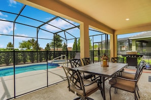 Eine überdachte Terrasse mit Pool, Grill und Sitzbereich.
