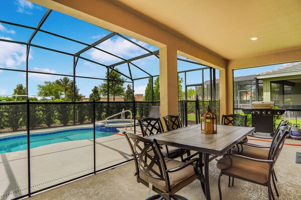 A covered patio with a pool, outdoor grill, and seating area. - 6BR Pool Home Near Disney at Solterra (Davenport)