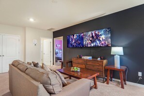 Ein Wohnzimmer mit einer Couch, einem Couchtisch, einem Fernseher und einer Lampe.