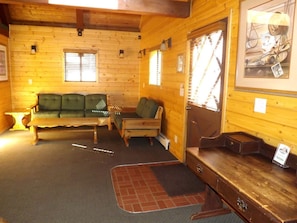 A wooden cabin interior with a sofa, a bench, a small table, and a framed picture on the wall. - Duplex Cabin with Spacious Interior Great for Groups in Arizona (Flagstaff)