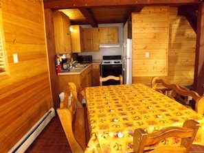 A wooden cabin interior with a dining table, chairs, a kitchen area, and a fireplace. - Duplex Cabin with Spacious Interior Great for Groups in Arizona (Flagstaff)