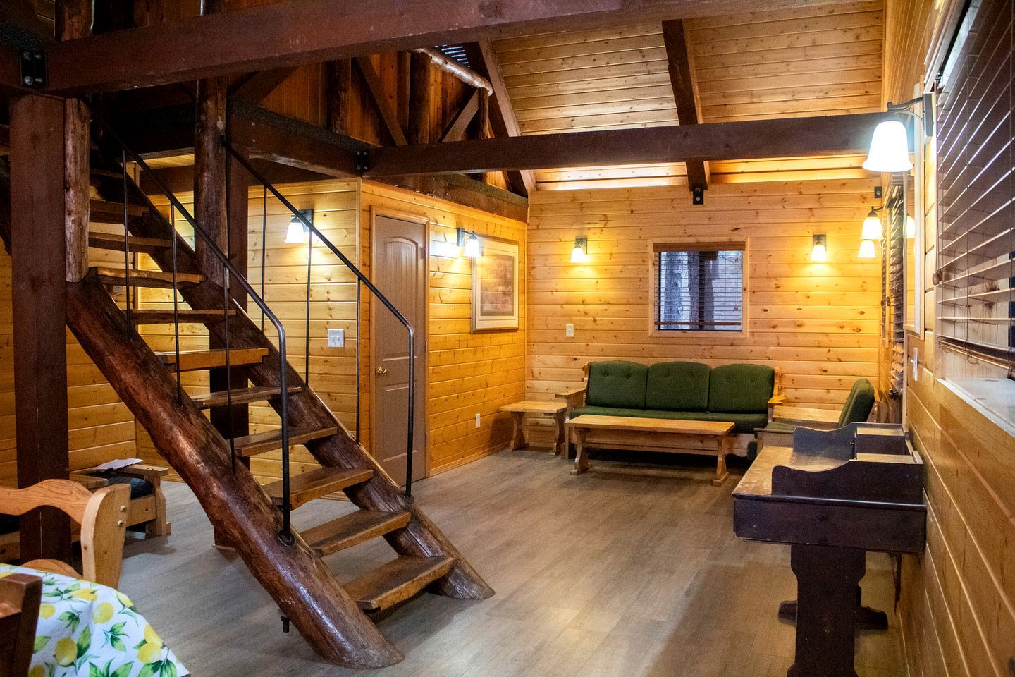 A wooden interior with a staircase, a green sofa, and a wooden table.