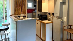 Uma cozinha moderna com ilha central, banquetas, micro-ondas e luminária pendente.