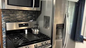 Una cocina con estufa, horno, microondas y refrigerador de acero inoxidable.