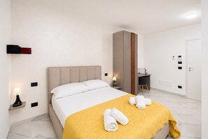 Ein Hotelzimmer mit Bett, Nachttischlampen, Schreibtisch und Kleiderschrank.