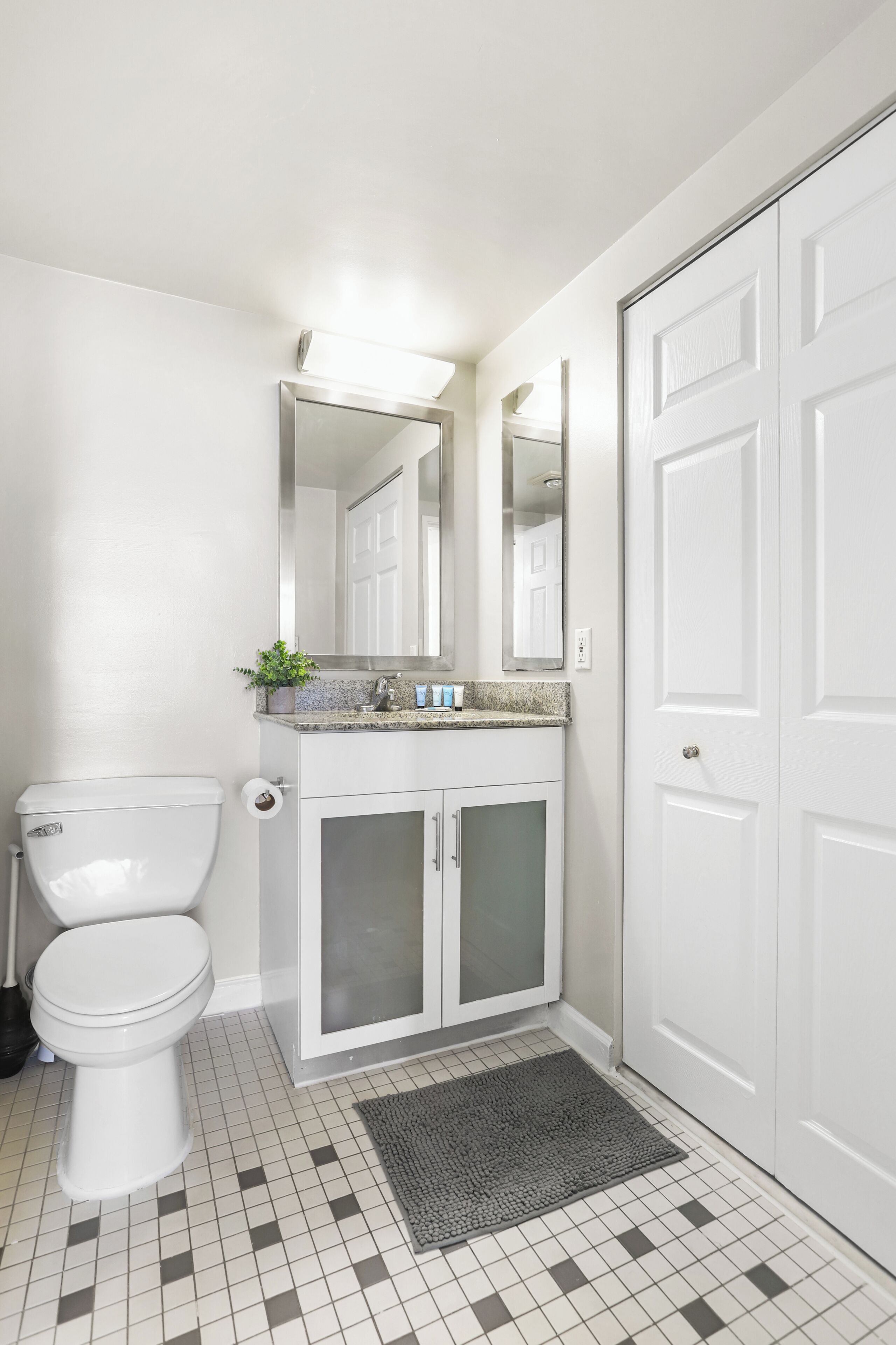 A bathroom with a toilet, a sink with a mirror, and a door.