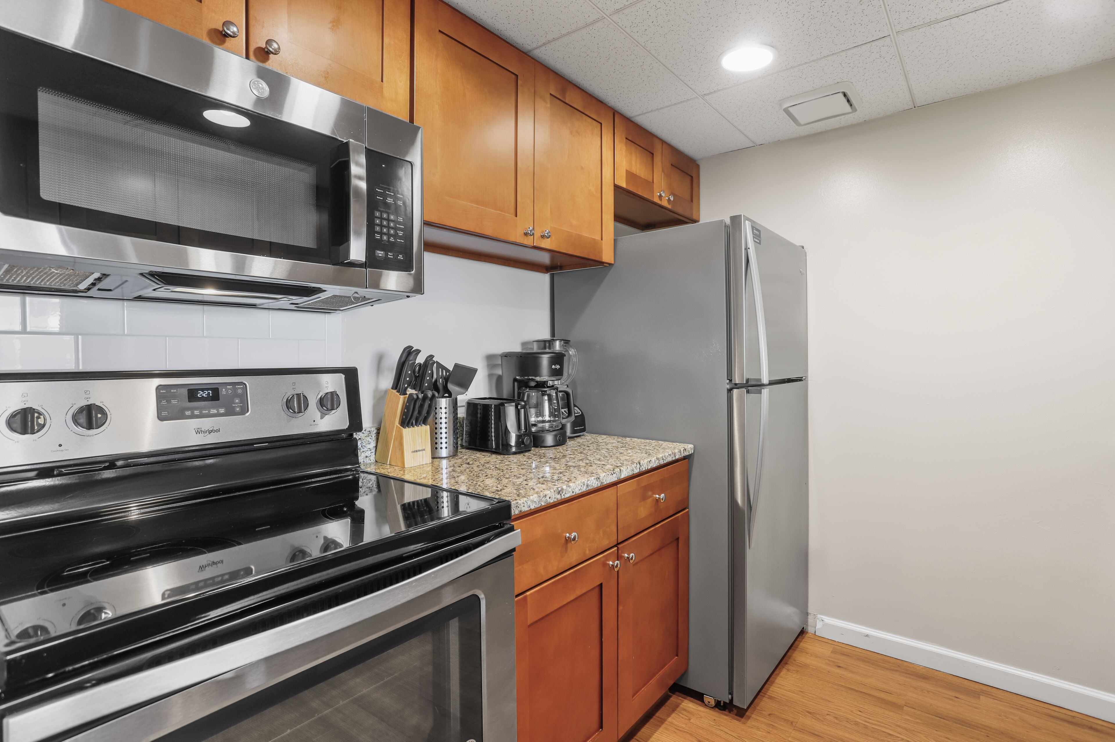 A kitchen with stainless steel appliances, wooden cabinets, and a granite countertop.