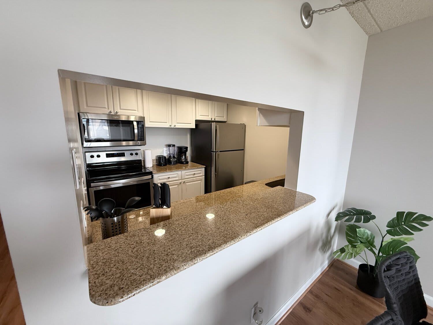 A modern kitchen with stainless steel appliances, a granite countertop, and white cabinetry.