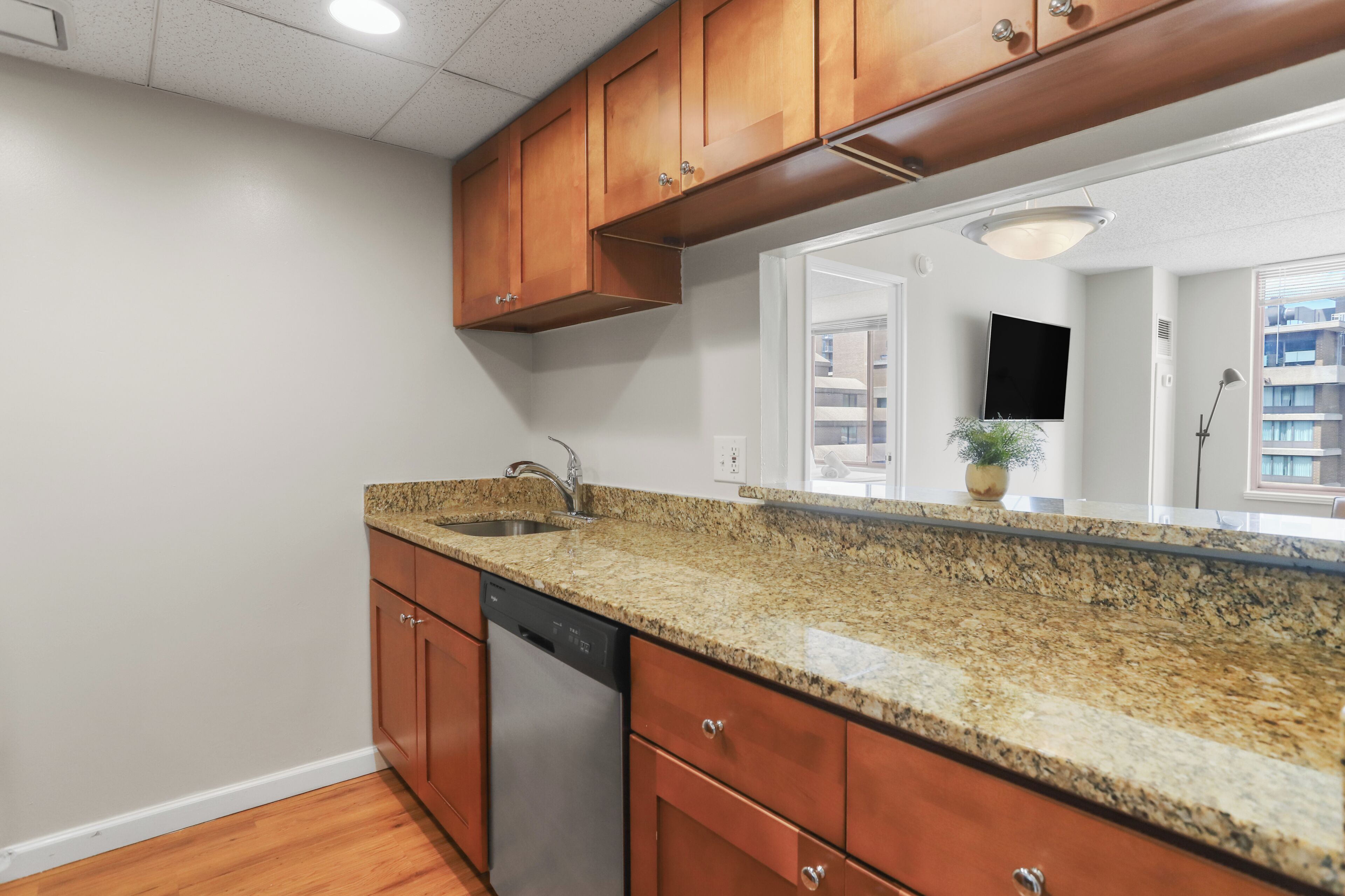 A kitchen with wooden cabinets, a granite countertop, a dishwasher, and a built-in oven.