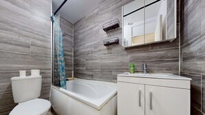 Une salle de bain comprenant des toilettes, une baignoire et un meuble avec des tiroirs.