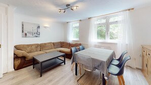 Un salon moderne avec un canapé, une table basse, une table à manger avec des chaises et un tableau accroché au mur.