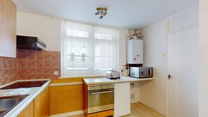 Une cuisine de taille réduite équipée d’une cuisinière, d’un four, d’un four à micro-ondes et d’une fenêtre avec des rideaux.