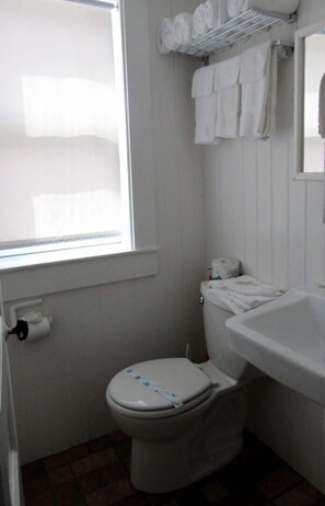A small bathroom with a toilet, a sink, a window, and a towel rack. - Seaside Escape with Coastal Vibes in North Truro, Massachusetts (North Truro)