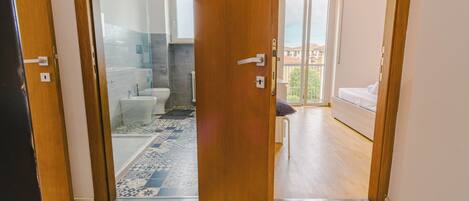 A room with a shower, toilet, and a bed.