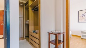 A room with a wooden wardrobe, a small table with a plate, and a framed picture on the wall. - Expo Smart Living - Two Bedroom Apartment, Sleeps 6 (Verona)