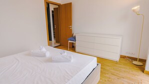 Ein Schlafzimmer mit einem Bett, einem Sessel, einem Heizkörper und einer Stehlampe.