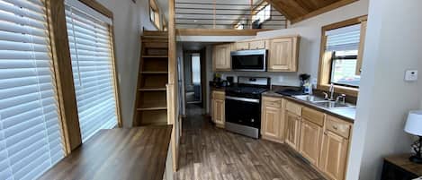 A compact kitchen with wooden cabinets, a built-in oven, and a dining area with a bench.