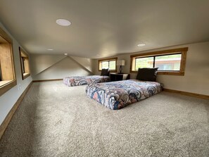 A bedroom with a large bed, a smaller bed, a window, and a ceiling vent.
