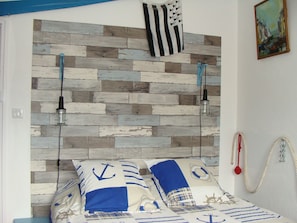 A bedroom with a wooden headboard, striped bedding, and nautical-themed decor.