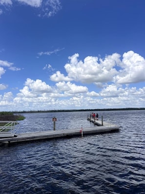 A dock extending into a lake with a clear sky and clouds.