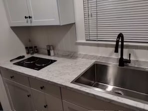 A kitchen with a sink, stove, cabinets, and a window with blinds. - Deco Studio Retreat: Fireplace, WiFi, Queen Bed (Reno)