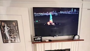 Ein Kamin mit darüber montiertem Fernseher, einer Uhr und einem gerahmten Bild an der Wand.