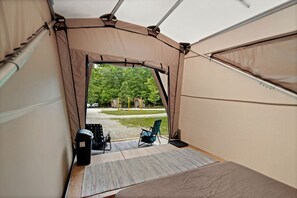 A tent with a view of a park and outdoor seating.