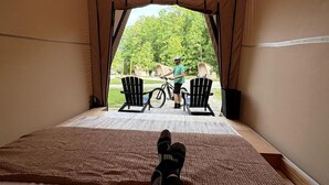 A tent with a view of a person on a bicycle outside, a chair, and a table.