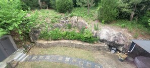 Ein Garten mit einer Steinmauer, einem Weg und einem kleinen Schuppen.