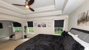 A bedroom with a large bed, a ceiling fan, two windows with blinds, a potted plant, and a painting on the wall. - Welcome to Atlanta: Old-Fashion Charm Meets Modern Retreat Near Airport (Atlanta)