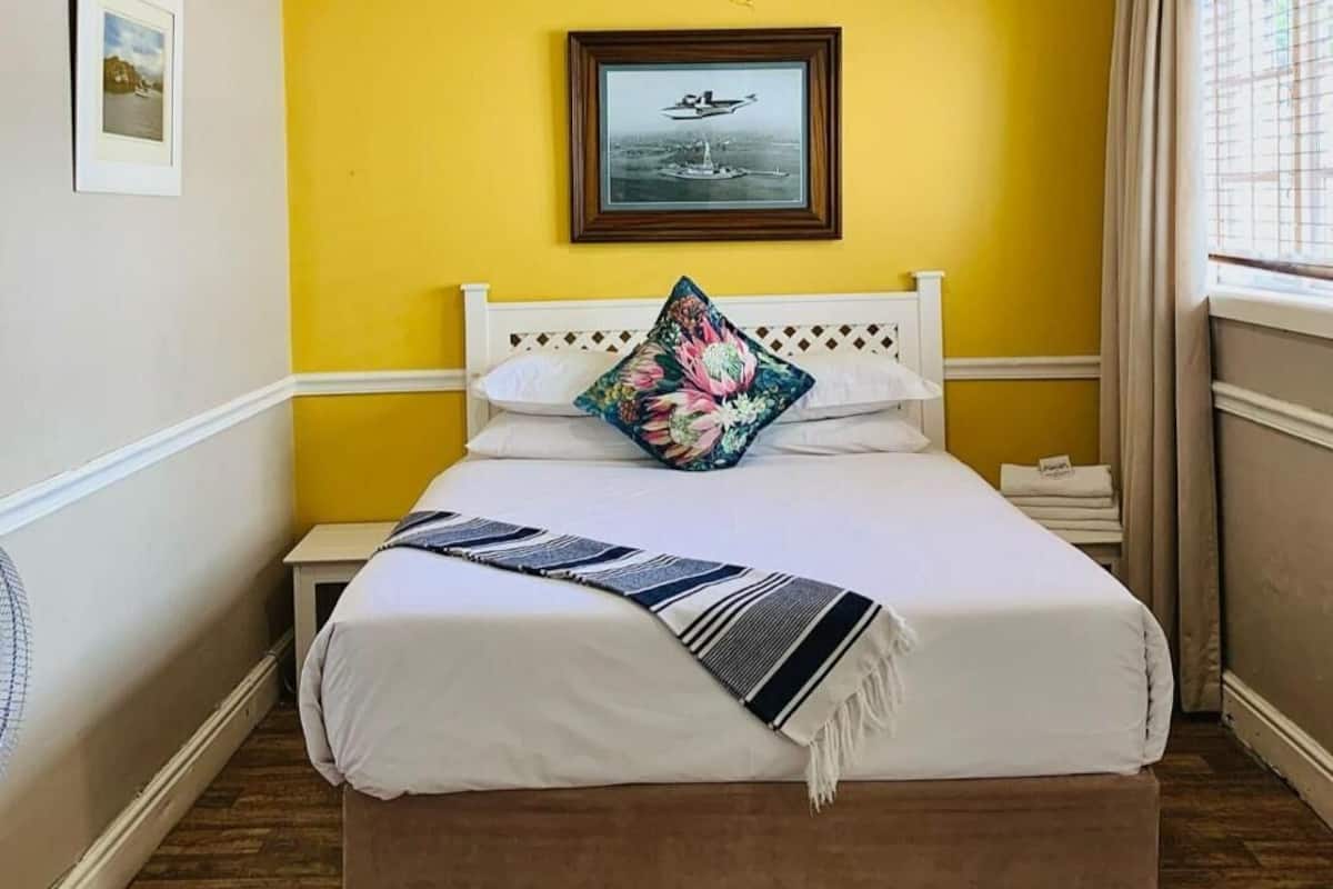 A bed with a white headboard, a floral pillow, and a striped blanket.