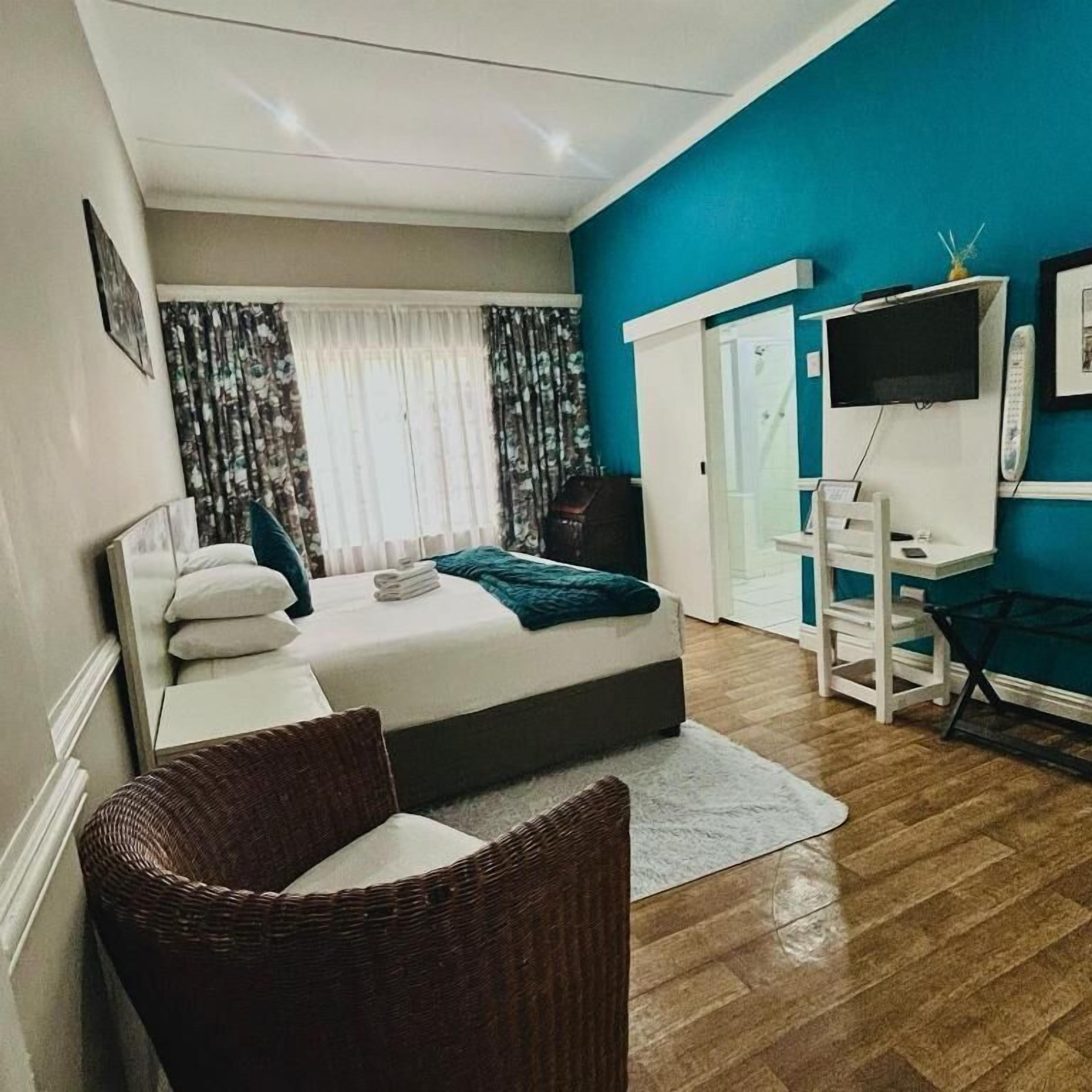 Een slaapkamer met een bed, een bureau, een stoel, een televisie en een kledingkast.