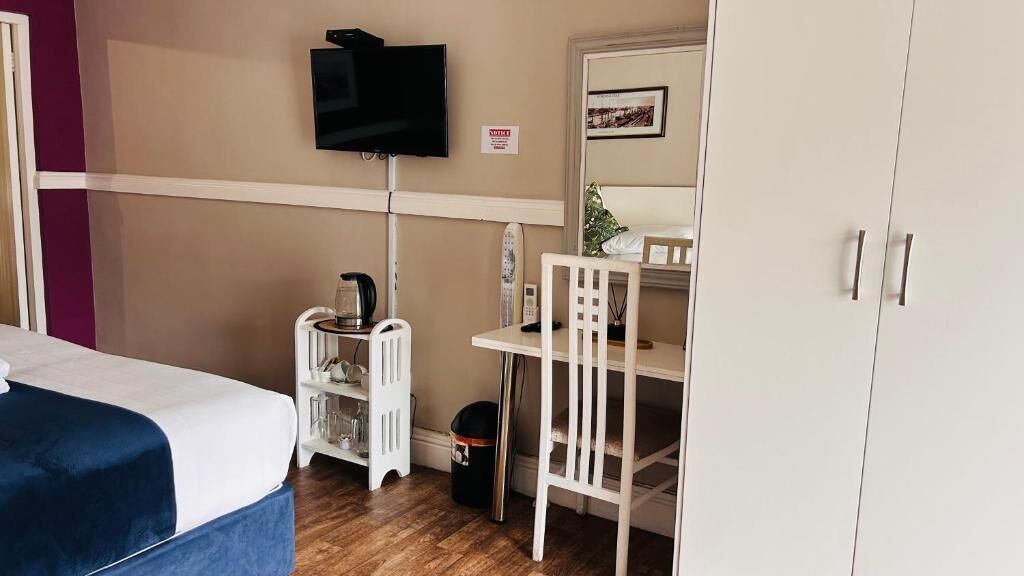 Ein Zimmer mit einem Bett, einem Schreibtisch, einem Stuhl, einem Fernseher und einem Kleiderschrank.