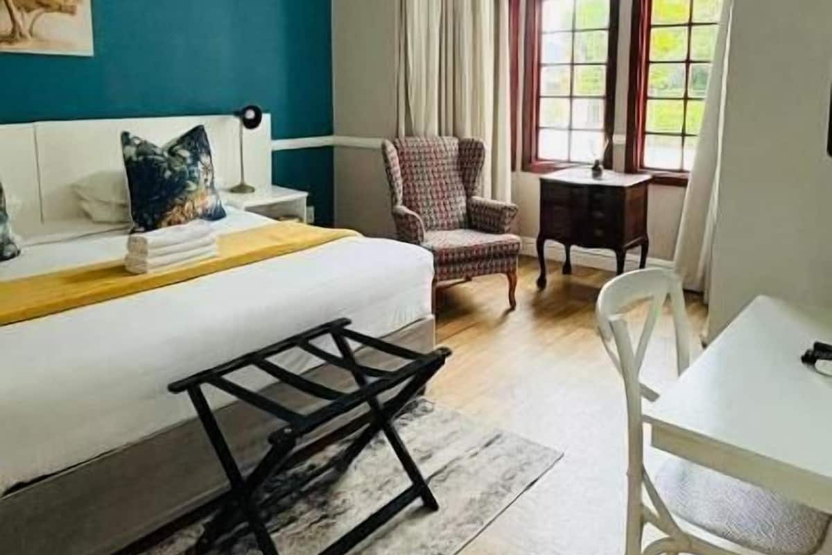 A room with a bed, a desk, a chair, and a window with curtains.