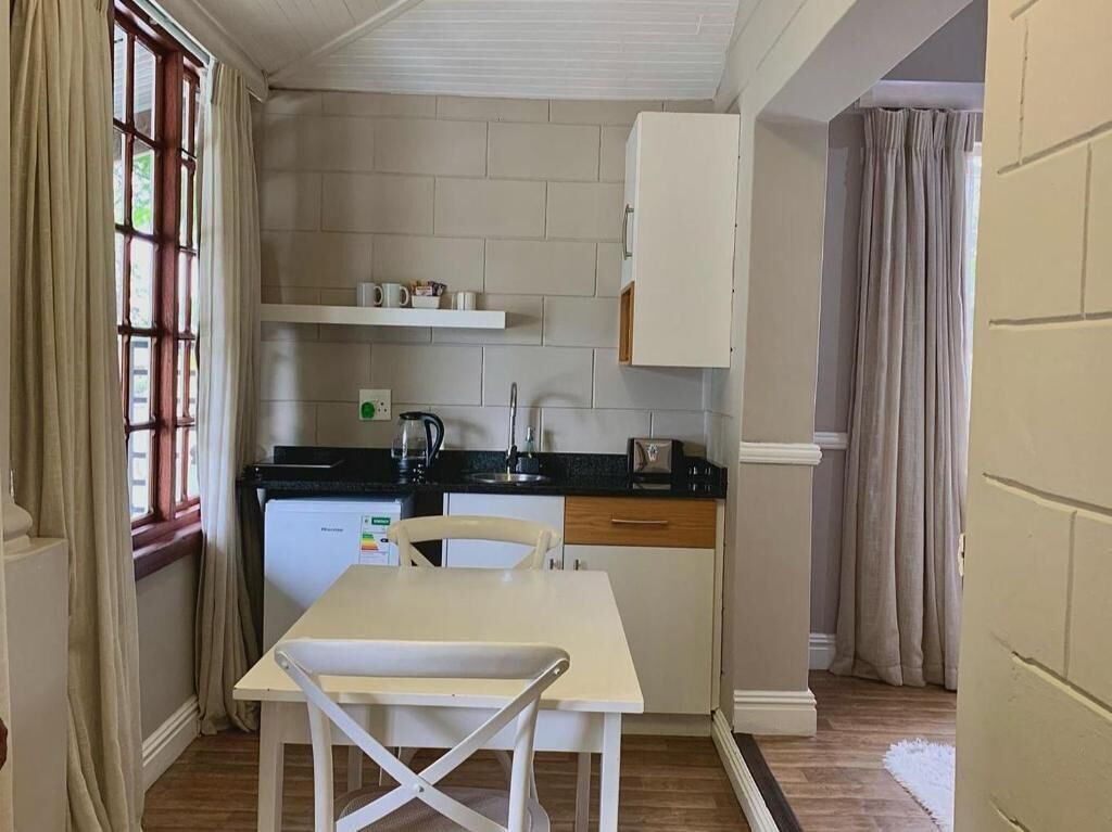 A compact kitchen with a white table, a black countertop, and a white cabinet above the sink.
