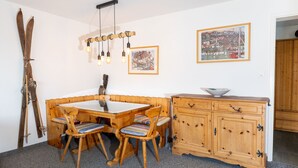 Ein Essbereich mit Holztisch und -stühlen, einem Holzschrank und einem Skiständer.
