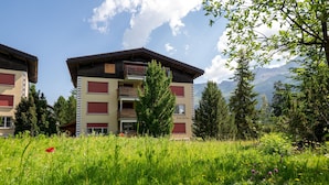 Ein Gebäude mit mehreren Balkonen, umgeben von üppiger Vegetation und Bergen im Hintergrund.