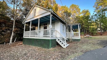 A two-story wooden cabin with a porch and a staircase leading to the upper level.